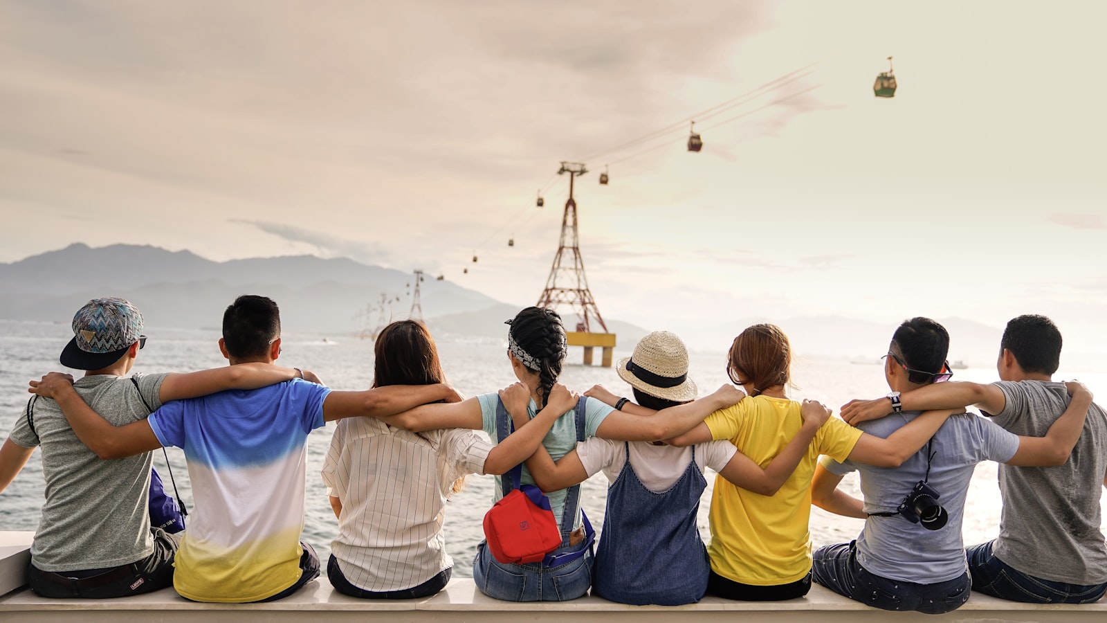 A group of friends sitting arm in arm, looking out at the water